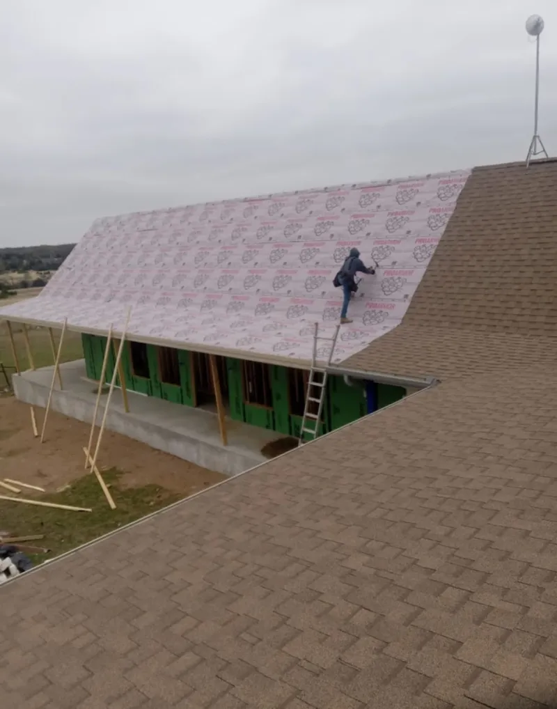 Worker preparing underlayment for a metal roof installation in Danville